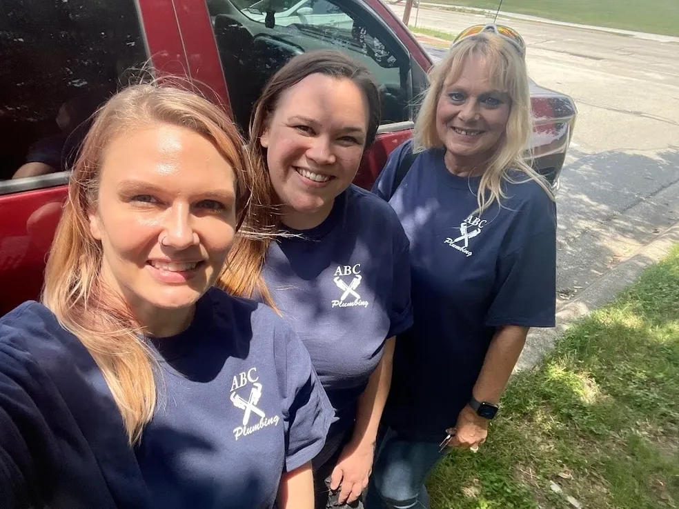 Three women standing next to a red van.