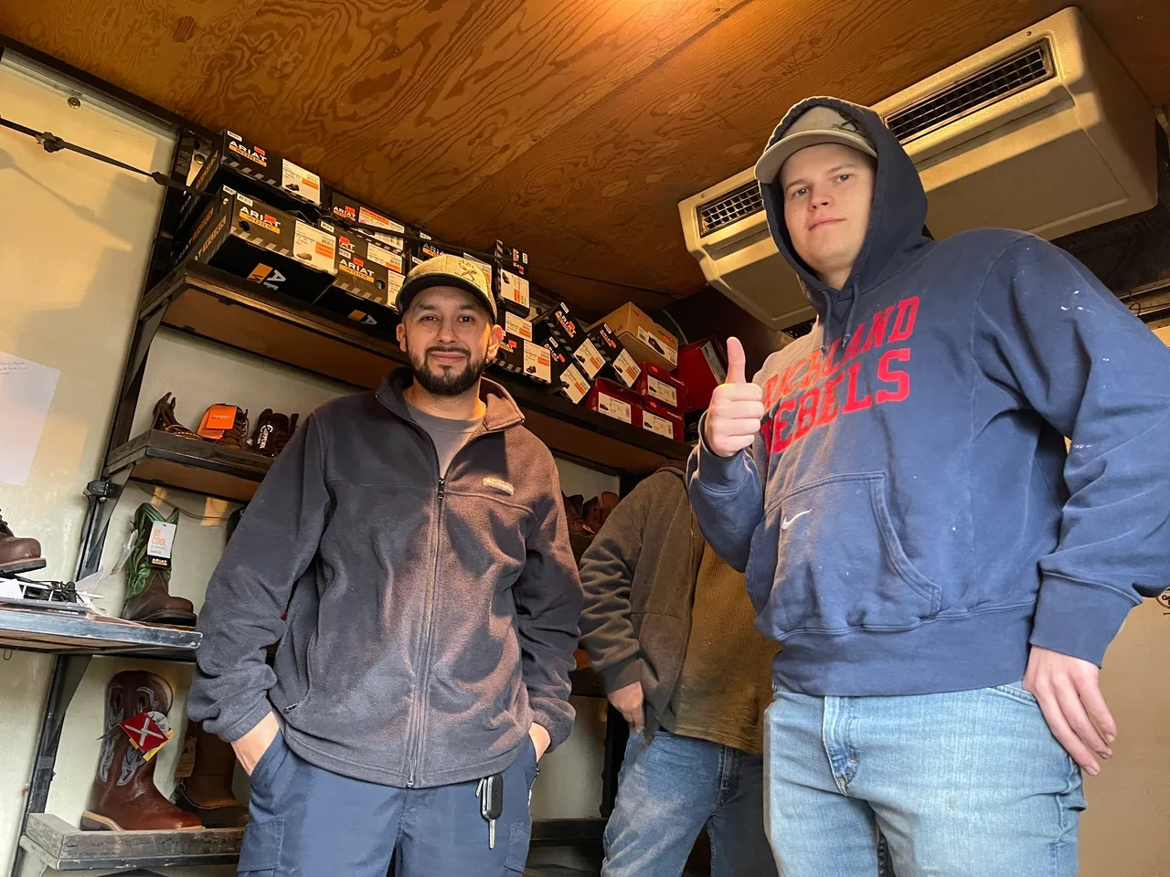 Two men in a room with shelves of shoes.