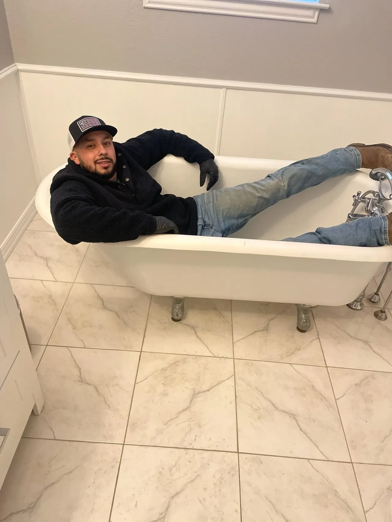 A man laying in the bathtub with his feet up.