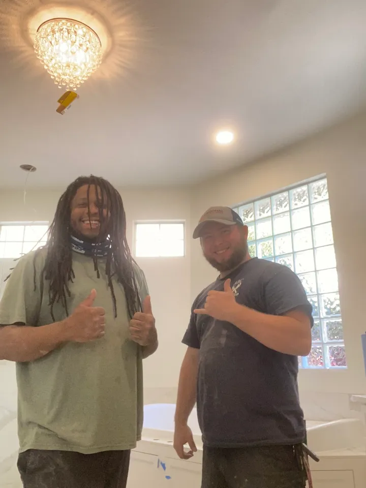 Two men standing in a room with thumbs up.