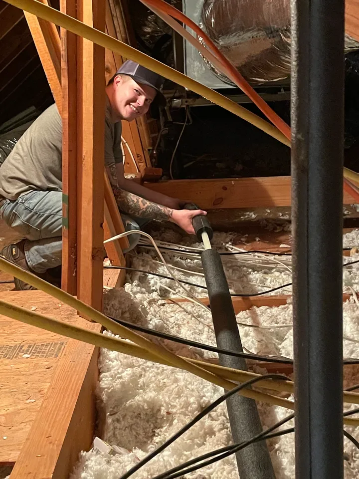 A man working on the inside of an attic.